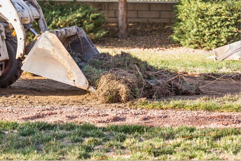 bobcat removing grass and soil to begin grading on back half of lot